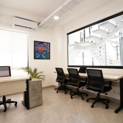 Private office suite featuring a wooden desk and a large window looking onto a modern internal staircase.
