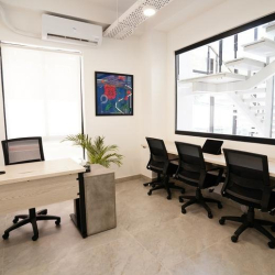 Brightly lit office space with a main desk setup and views of an architectural metal staircase.