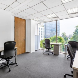 Open plan office workspace with desks and windows overlooking city greenery, Hanoi, Vietnam.