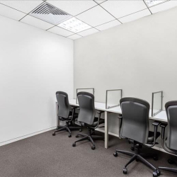 Shared workroom with multiple desks and chairs against a white wall, Hanoi, Vietnam.