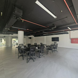 Meeting room with a long black table and ergonomic chairs under an industrial ceiling.