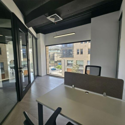 Functional workspace with four desks and industrial red pipe accents.