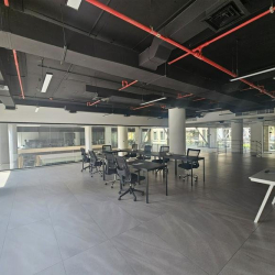 Large open-plan office with multiple desks and floor-to-ceiling windows.