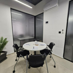 Intimate meeting space with a small round table and chairs in glass-walled office.