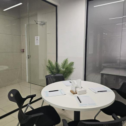 Round discussion table with office chairs in a glass-walled enclosure.