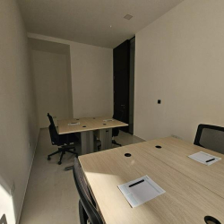 Minimalist office with wooden desks and a narrow layout.