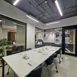 Modern meeting room with a white table, plants, and glass walls.
