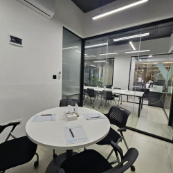 Small round meeting table with black chairs in a glass-walled room.