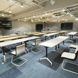 Versatile seminar space with modular white tables and multiple wall-mounted monitors.