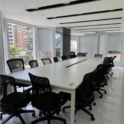 Professional boardroom with a long white conference table and ergonomic black chairs.