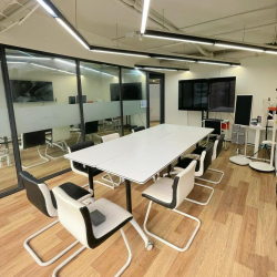 Contemporary meeting room with a white table, stylish chairs, and dual presentation screens.