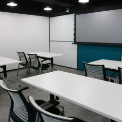 Training or classroom setup with several white tables and ergonomic chairs.