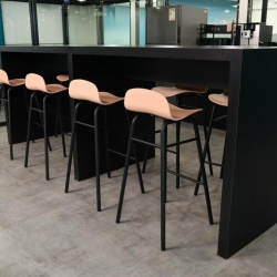 Communal breakout area with a high black table and modern wooden stools.
