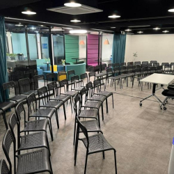 Large seminar room with rows of black chairs and a presentation table.