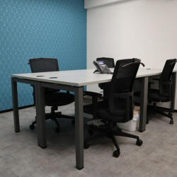 Compact meeting room with four black mesh chairs and a teal accent wall.