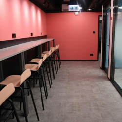 Long high-top workspace with stools against a coral pink wall.