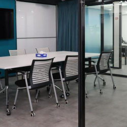 Glass-walled conference room featuring a large table and wall-mounted screen.