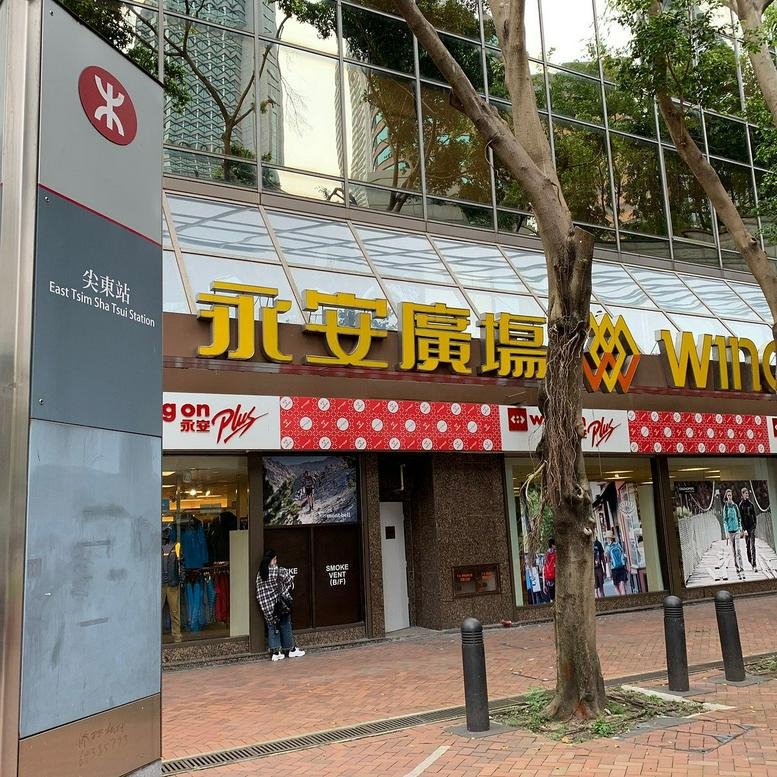 Exterior street-level view of Wing On Plaza building entrance with yellow signage and storefronts.