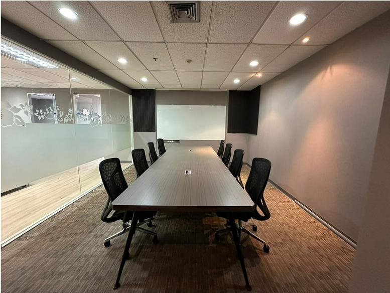 Professional boardroom at Serm Mit Tower with long grey table and black mesh chairs.