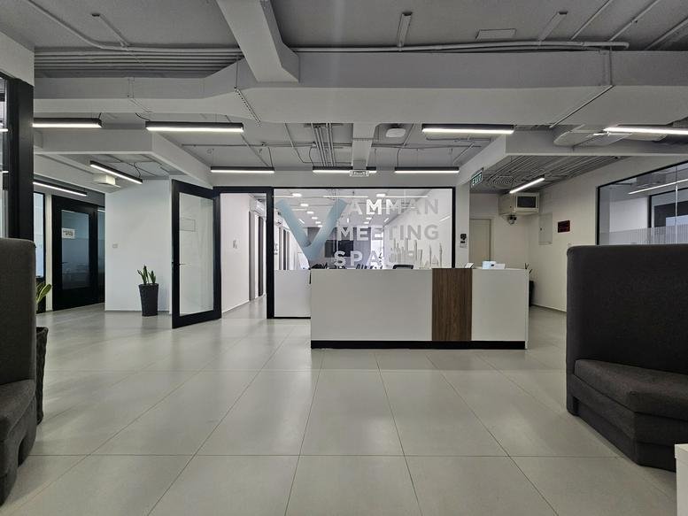 Reception area with a modern white desk and glass partitioned doors.