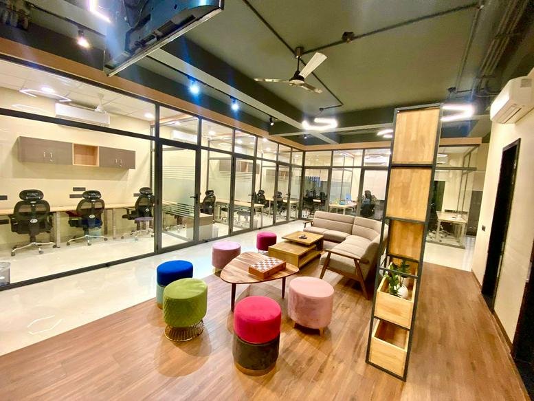 Spacious communal lounge at 150/21, Creware Lane, Shipra Path with colorful stools and a wooden bookcase.