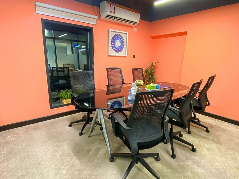 Meeting room at World Wide Commercial Building, Al Hilal with a glass table and orange walls.